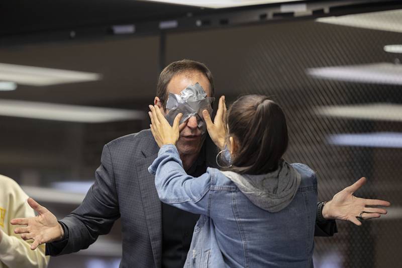 Sauk Valley Community College student Michelle Gutierrez checks the duct tape and silver dollars placed over the eyes of mind reader Christopher Carter on Wednesday, Nov. 16, 2022.