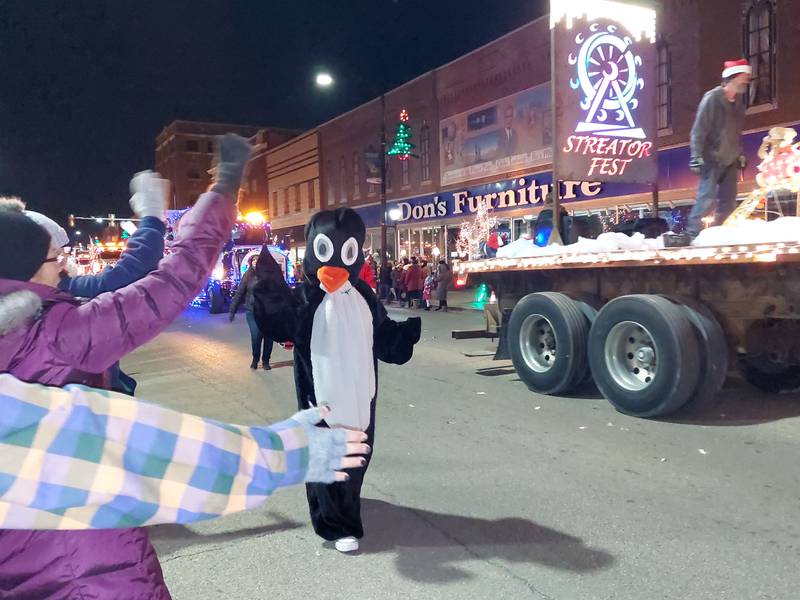 A penguin gets cheers and high fives as it walks the parade route Saturday, Nov. 25, 2023, during the Streator Lighted Christmas Parade.