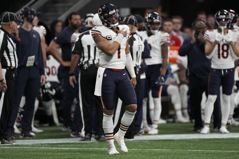 Chicago Bears quarterback Justin Fields holds his shoulder after a hard tackle by an Atlanta Falcons defender late in the second half, Sunday, Nov. 20, 2022, in Atlanta.