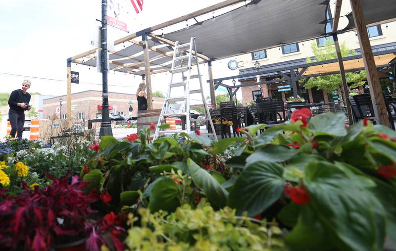 Workers with Skoogs build patio furnature and hang plants for Mill Street dining on Friday, May 8, 2026 downtown Utica. The road will be closed to traffic until late October.