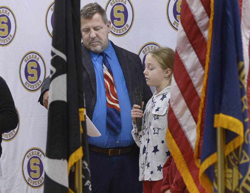 Assisted by Superintendent Rich Faivre, Olive Young of Harding Grade School reads her student essay thanking veterans during a Veterans Recognition Ceremony Tuesday at Serena High School.