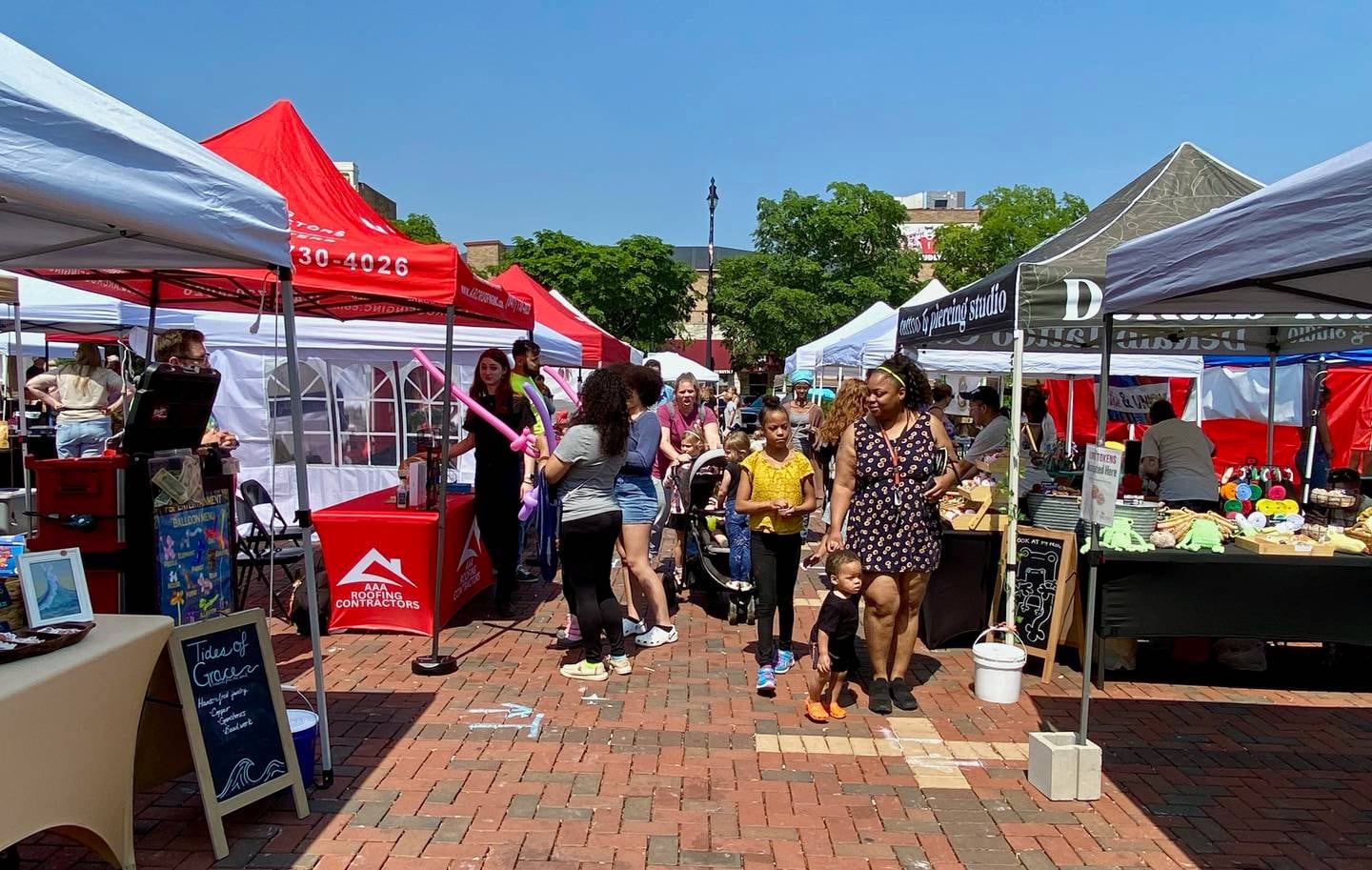 Families browse vendor stands during the opening day of the DeKalb farmers market on Thursday, June 5, 2025, in Van Buer Plaza in downtown DeKalb. The market opened its 30th year Thursday.