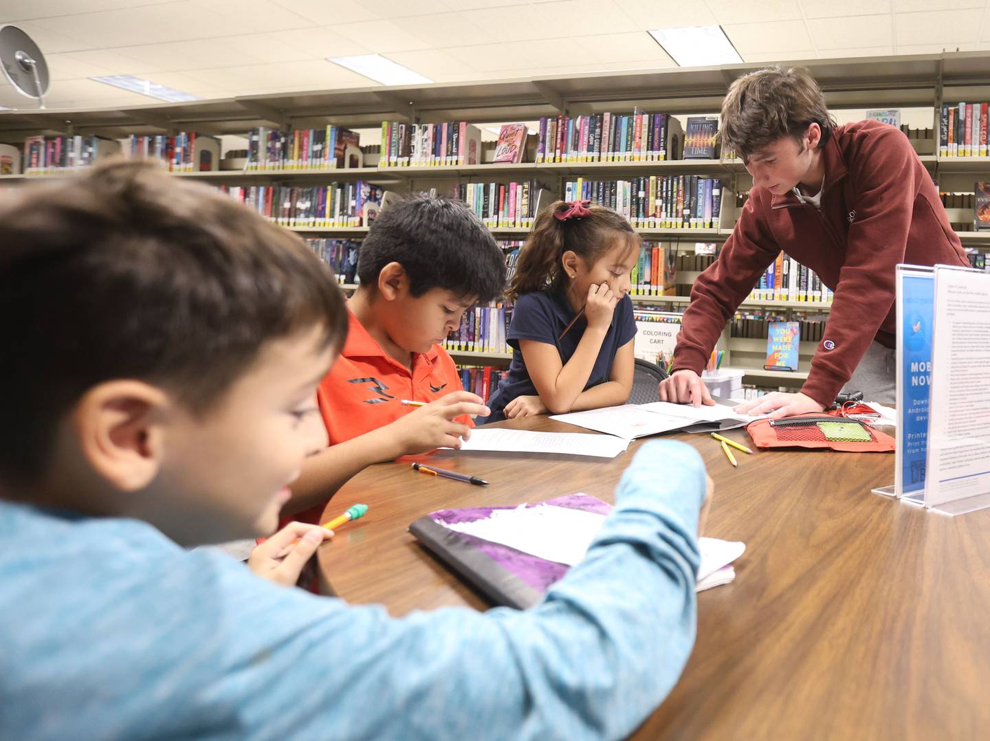 Ryne Bubela a junior at La Salle-Peru Township High School, helps tutor kids Joel Berrum Jr., Jesus Garcia and Elvira Berrum on Tuesday, Nov. 4, 2025 at the Peru Library. Bubela started the Illinois Valley Learning Hub, a volunteer tutoring program that offers free academic help to elementary and middle school students.