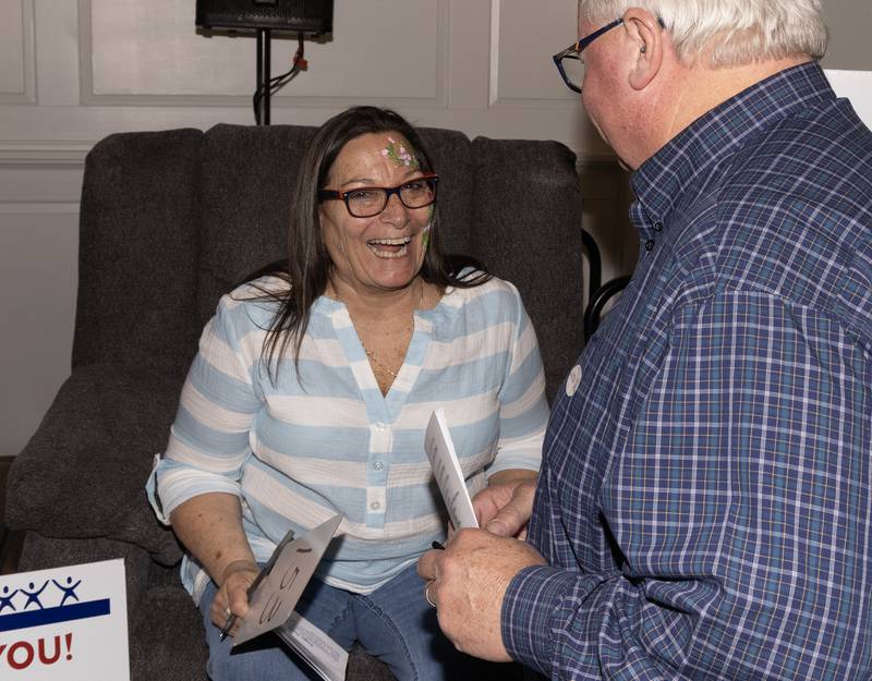 La Salle County CASA Executive Director CiCi Chalus shares a laugh with volunteer Dan Aussem as she demonstrates the comfort of a recliner donated by Steinberg's Furniture during the live auction Sunday, April 21, 2024.