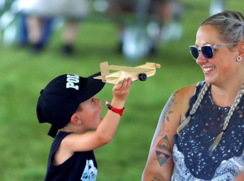 Rowan LaTessa, 4, of Wonder Lake shows his mother Crystal a wooden toy plane he built during Fiesta Days at Petersen Park in McHenry Sunday. LaTessa constructed the craft as part of a Home Depot craft booth.