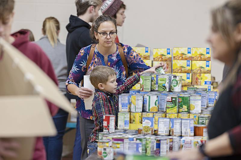 Danelle Burrs and son Grant, 5, pack food boxes Tuesday, Dec. 20, 2022 at the Dixon YMCA. Through community members, businesses and organizations, the YMCA lead the charge to gather food items that will go to local families this holiday season.
