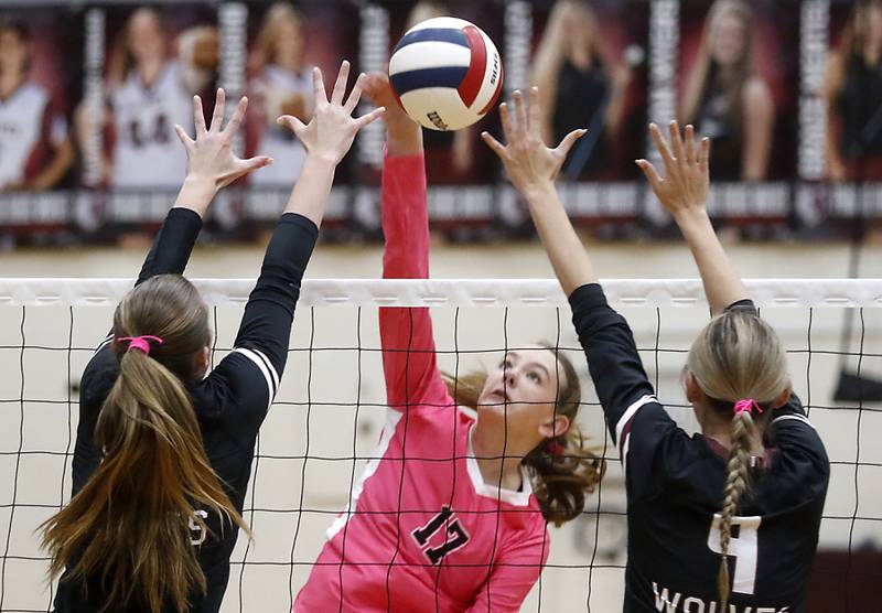 Huntley's Lucy Watson (center) hits the ball between the block of Prairie Ridge's Ella Glover-Taylor (left) and Prairie Ridge's Harleigh Serpico (right) during a Fox Valley Conference volleyball match on Tuesday, Oct. 14, 2025, at the Prairie Ridge High School in Crystal Lake.