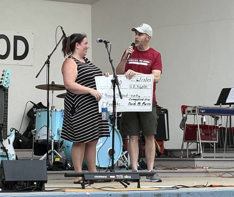 Bruce McKanna, pastor of the Evangelical Free Church of Mt. Morris, presents a check to Let Freedom Ring Committee Chairman Catherine Higley at the June 13 Jamboree. The final amount of the donation was $2,871, 100 percent of the donations received at the church's food concession that evening.