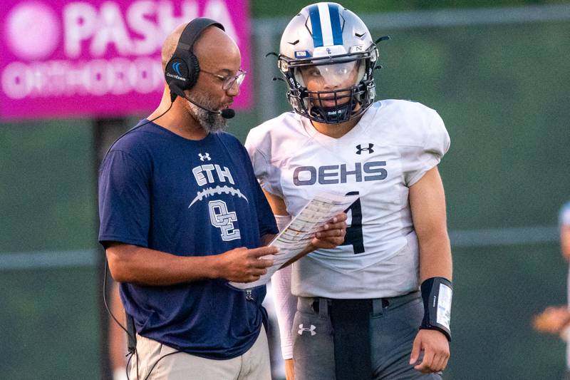 Oswego East's head coach Tyson LeBlanc gives instructions to Niko Villacci (4) during a football game against Waubonsie Valley at Waubonsie Valley High School in Aurora on Friday, Aug. 25, 2023.