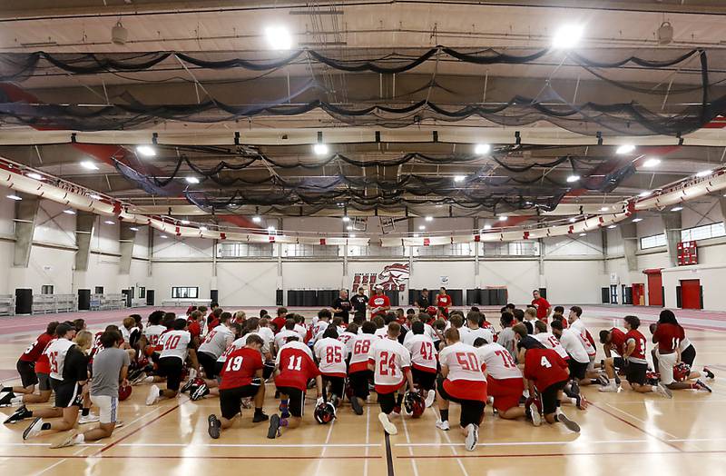Huntley’s new coach Mike Naymola speaks to the team during the first day of football practice Monday, 8, 2022, in the Huntley High School  field house after stormy weather move practice inside.