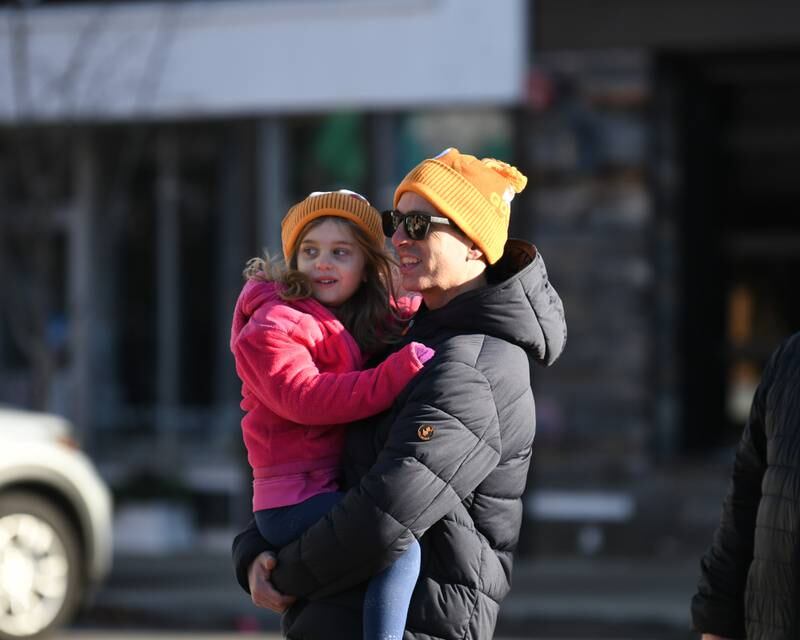Jeff Kok-Alblas holds his daughter Isla Kok-Alblas, 5, of Downers Grove as they wait for their participant to run by during the Grove Express 5k race held in downtown Downers Grove on Thursday Nov. 23. 2023.