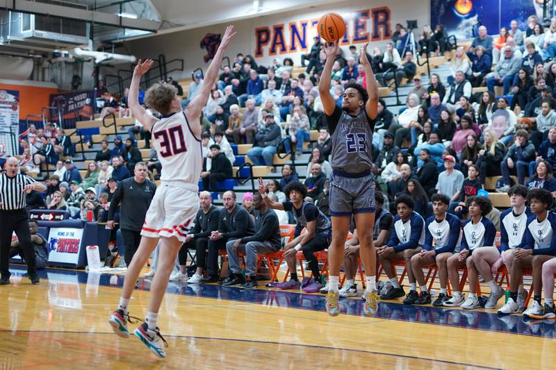 Oswego East's Torrin Ross (23) shoots a 3-pointer against Oswego’s Brayden Borrowman (30) during a basketball game at Oswego High School on Tuesday, February 18, 2025.