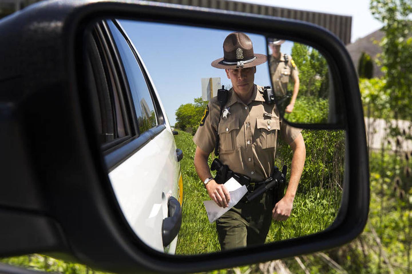 For his own safety, Trooper Dan Kenshol walks along the outside shoulder to minimize exposure to traffic on Thursday, May 23, 2019, on Interstate 55 in Joliet, Ill. Scott's Law is named after Lieutenant Scott Gillen of the Chicago Fire Department who was struck and killed by an intoxicated driver while assisting at a crash. It requires drivers approaching police or emergency vehicles who are stopped on the roadway to reduce speeds, proceed with caution and switch lanes, if possible.