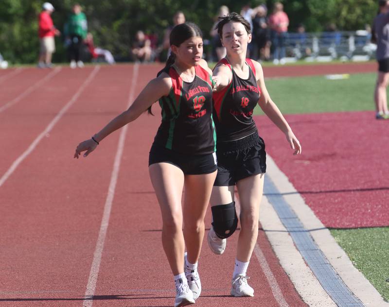 L-P's Hope Garncarz receives the baton from teammate Clara Weitl in the 4x800 relay during the Interstate 8 Conference girls track championship on Friday, May 9, 2025 at Morris High School.