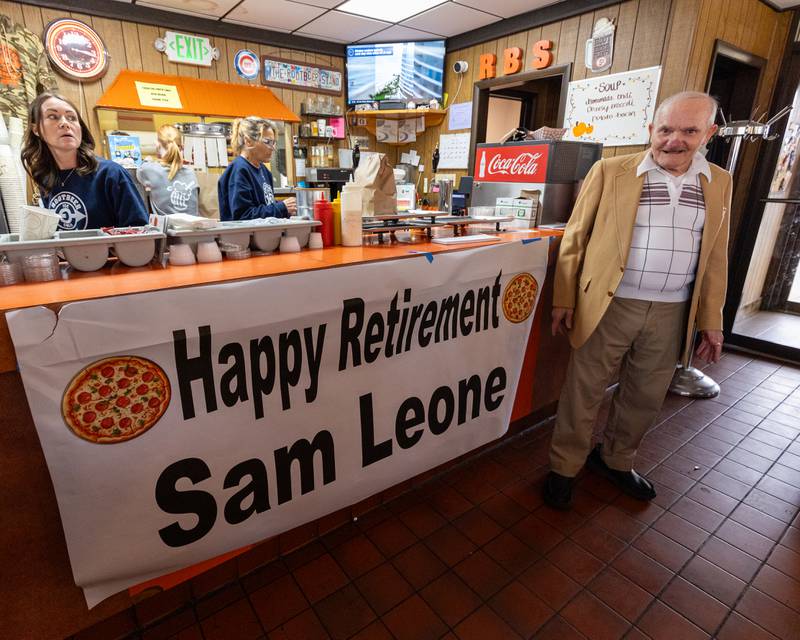 Sam Leone stands next to banner at his retirement celebration on Saturday, October 25, 2025 at the Rootbeer Stand in Oglesby.