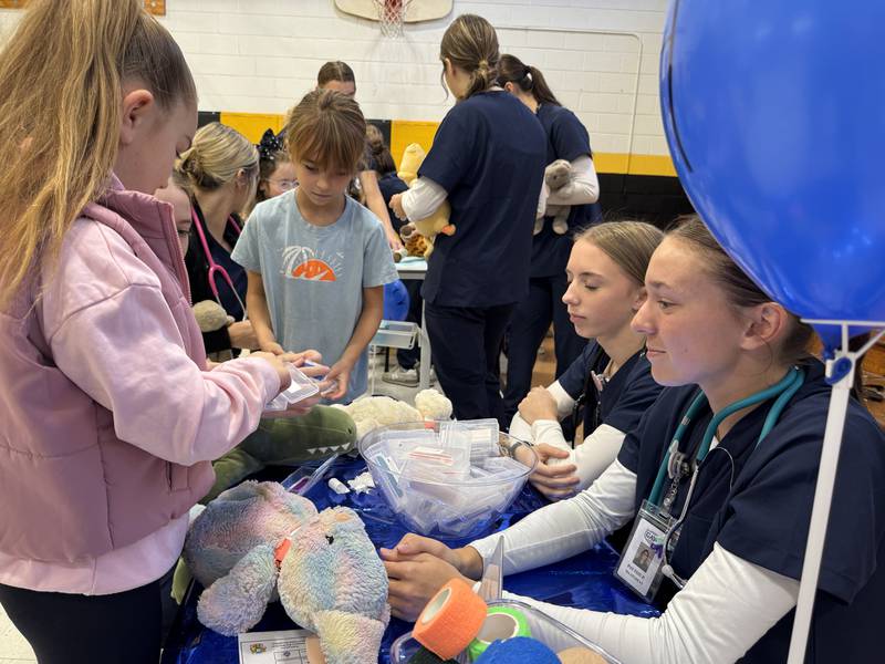 A Grundy Area Vocational Center health occupations student shows a Nettle Creek School student how to apply a bandage to her stuffed animal. Photo taken on Wednesday, Nov. 11, 2025.