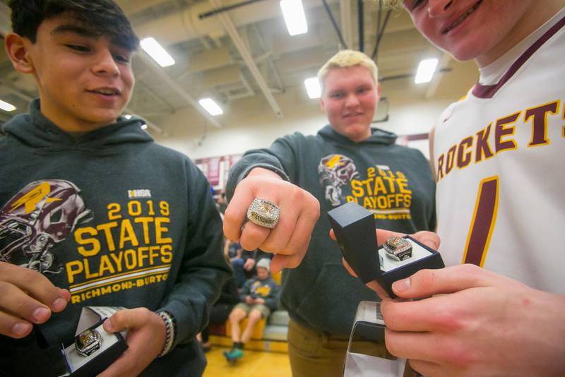 Richmond-Burton's Reymundo Guajardo (left) and Logan Hutson (right) watch as Logan Grant shows off his Class 4A football state championship ring players and coaches received during halftime of R-B's boys basketball game against Woodstock North on Tuesday in Richmond.
