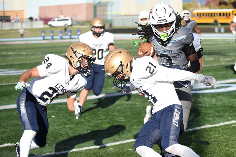 Kankakee's Cedric Terrell III, right, evades tackle attempts from Lemont's Jakub Maka, left, and Ewald Trickle during an IHSA Class 5A playoff game at Kankakee Saturday, Nov. 1, 2025.