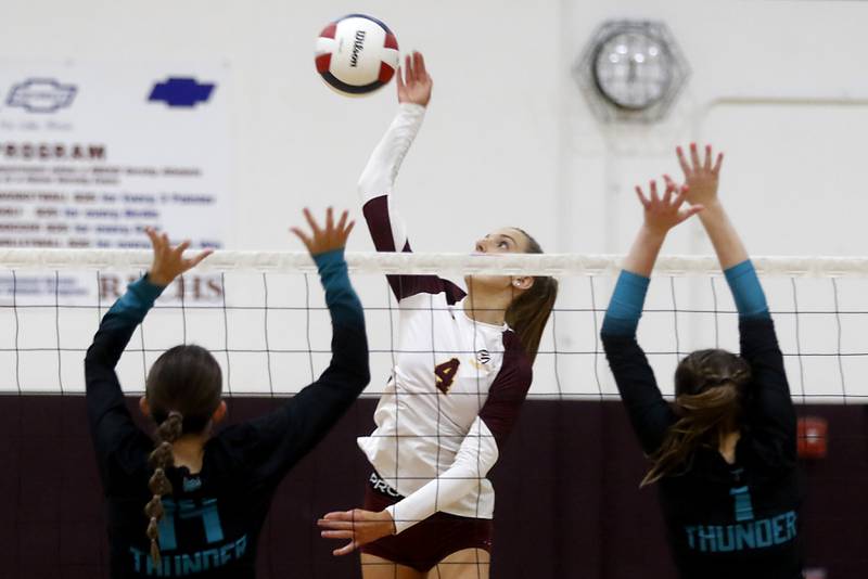 Richmond-Burton's Daniella Hopp (center) hits the ball between Woodstock North's Alyssa Martin (left) and Tayler Menzel (right) during a Kishwaukee River Conference volleyball match on Wednesday, Oct. 15, 2025, at the Richmond-Burton High School in Richmond.