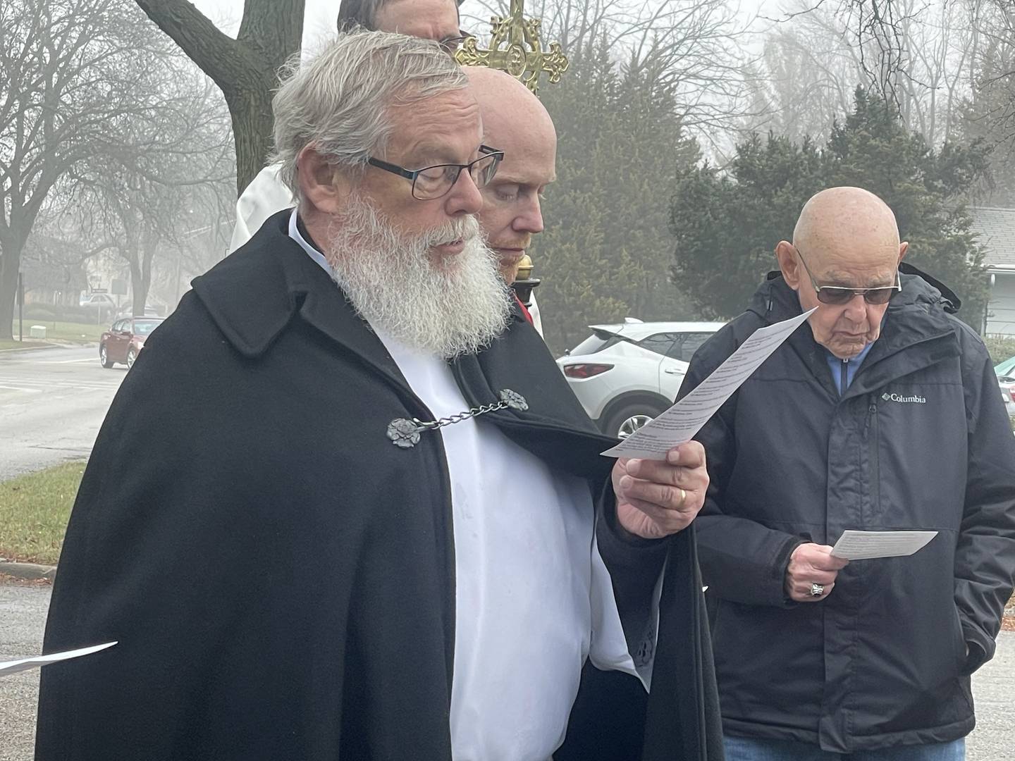 Ron Larson (left), a visiting clergy from Mt. Morris, presides over a dedication ceremony Sunday, Dec. 15, 2024, for a new little free library installed outside St. Paul's Episcopal Church in DeKalb.