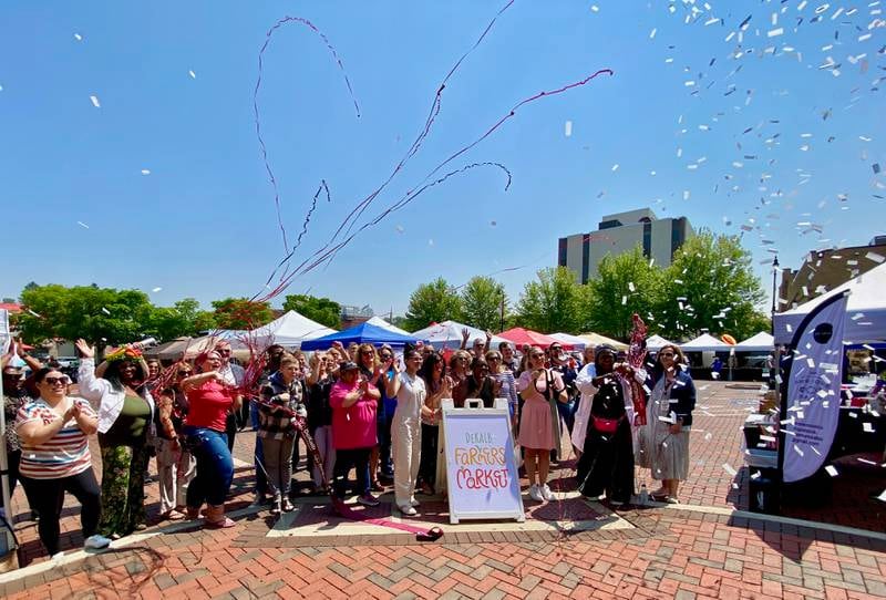 Business owners and members of the DeKalb Chamber of Commerce cheer as a ribbon is cut by the chamber's marketing and events manager Virginia Filicetti to celebrate the 30th year of the DeKalb farmers market on Thursday, June 5, 2025.