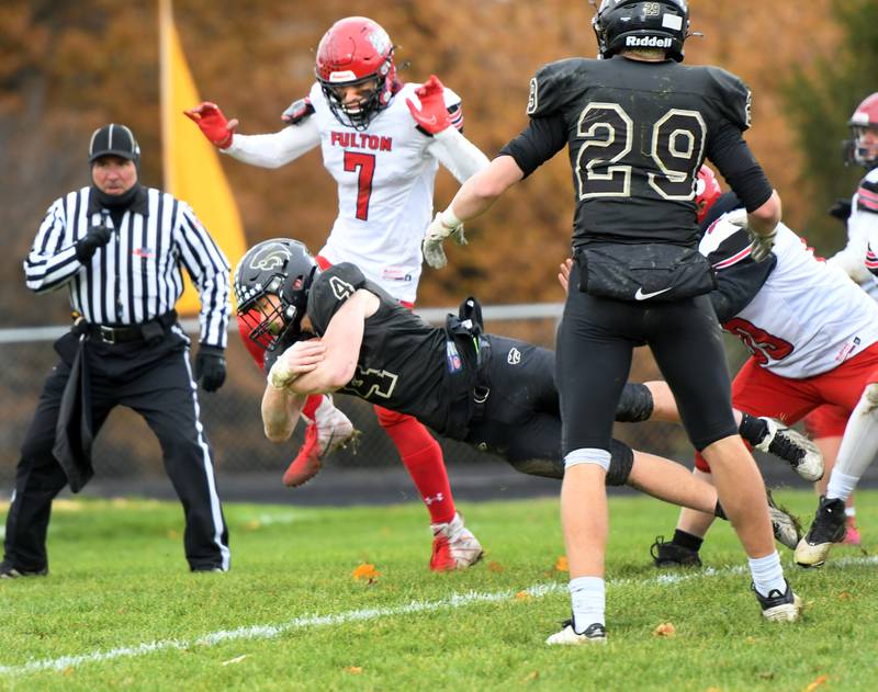 Lena-Winslow's Gage Dunker dives into the end zone as Fulton's Jacob Jones gets ready to jump over him during 1A state playoffs on Saturday.