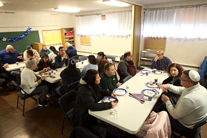 Members visit during a Chanukah party at The McHenry County Jewish Congregation Sunday.