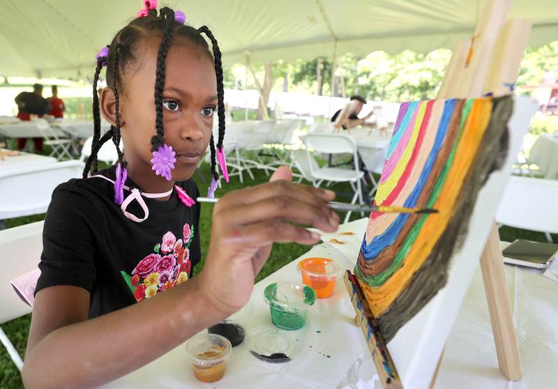 Jaylene Bell, 7, from DeKalb, creates a painting during the second annual Juneteenth celebration Sunday, June 19, 2022, at Hopkins Park in DeKalb.