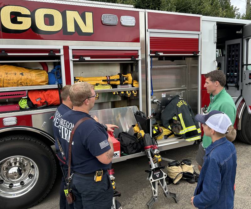 Ben and David Hammer of Oregon talk to Oregon firefighters at National Night Out, hosted by the Oregon Police Department and Oregon Park District at River's Edge Experience in Oregon on Tuesday, Aug. 6, 2024.