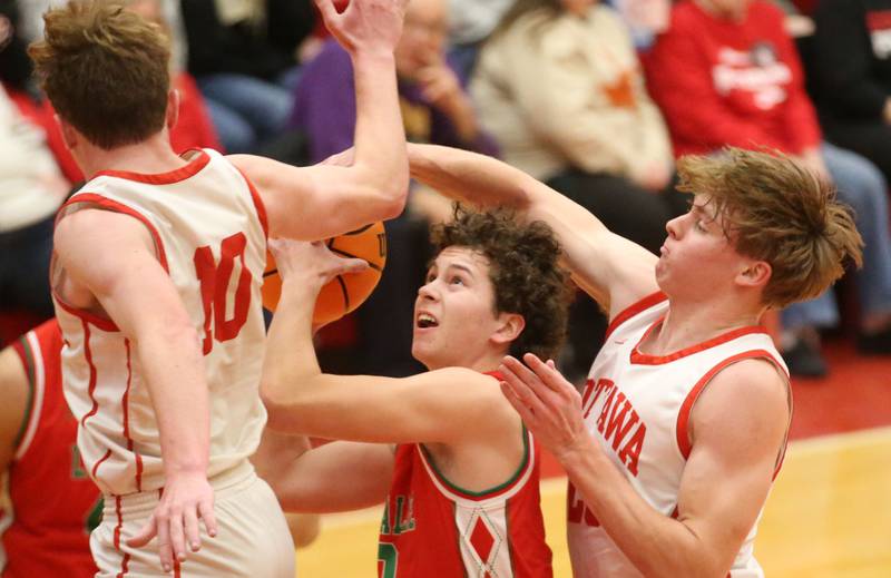 L-P's Mikey Hartman is fouled in the lane by Ottawa's Owen Sanders and Evan Snook on Friday, Jan. 10, 2024 in Kingman Gym at Ottawa High School.