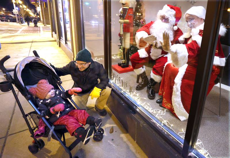 Dave Smith and his daughter Sterling, 3, from Sycamore, wave to Santa and Mrs. Claus in the window of Sycamore Center Friday, Nov. 18, 2022, during the Sycamore Chamber of Commerce's annual Moonlight Magic event in downtown Sycamore.