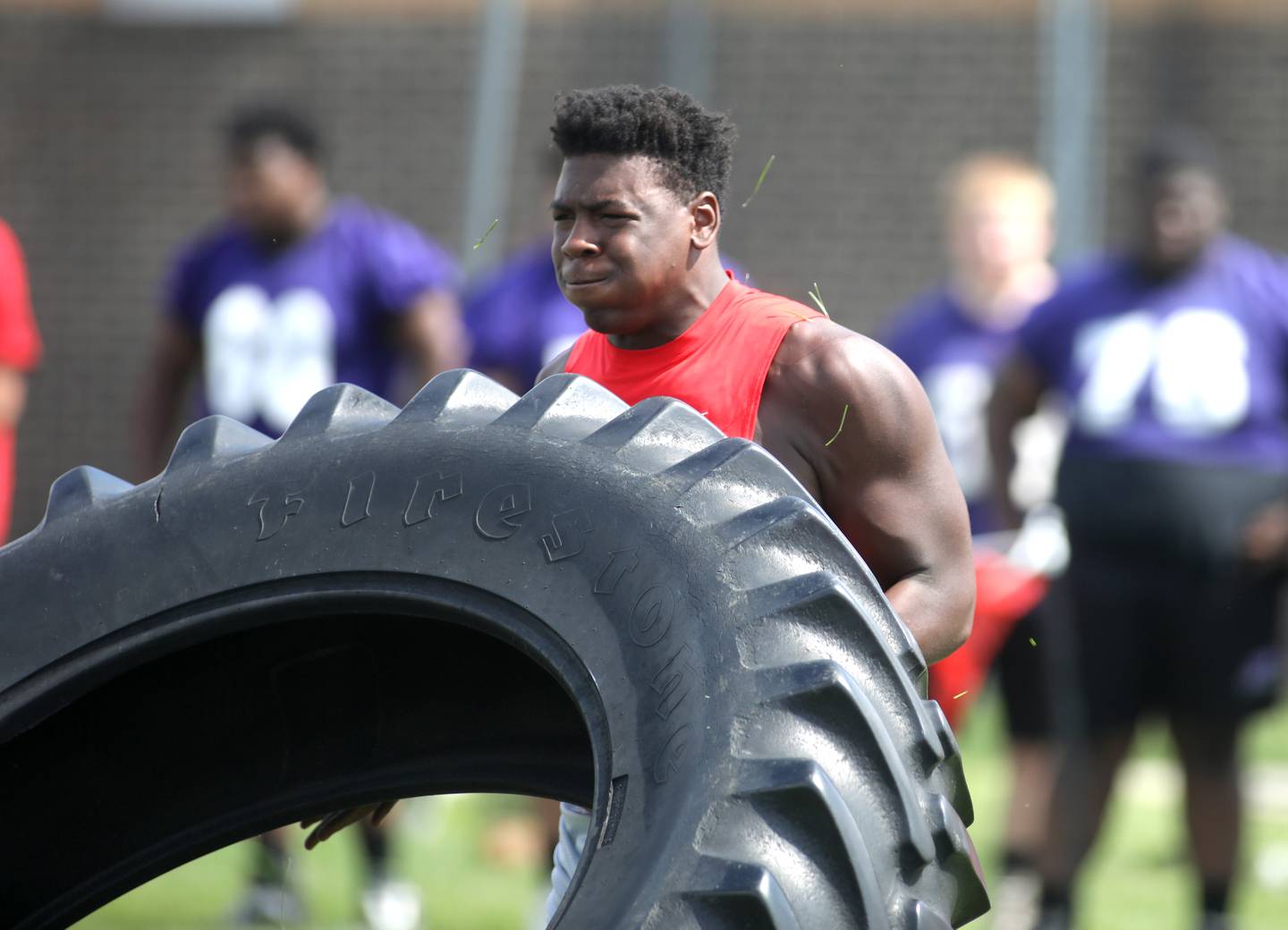 Batavia’s Jordan Buckley picks up a giant tire as part of the annual "Battle of the Big Butts" Linemen Challenge at West Aurora High School on Thursday, July 13, 2023.