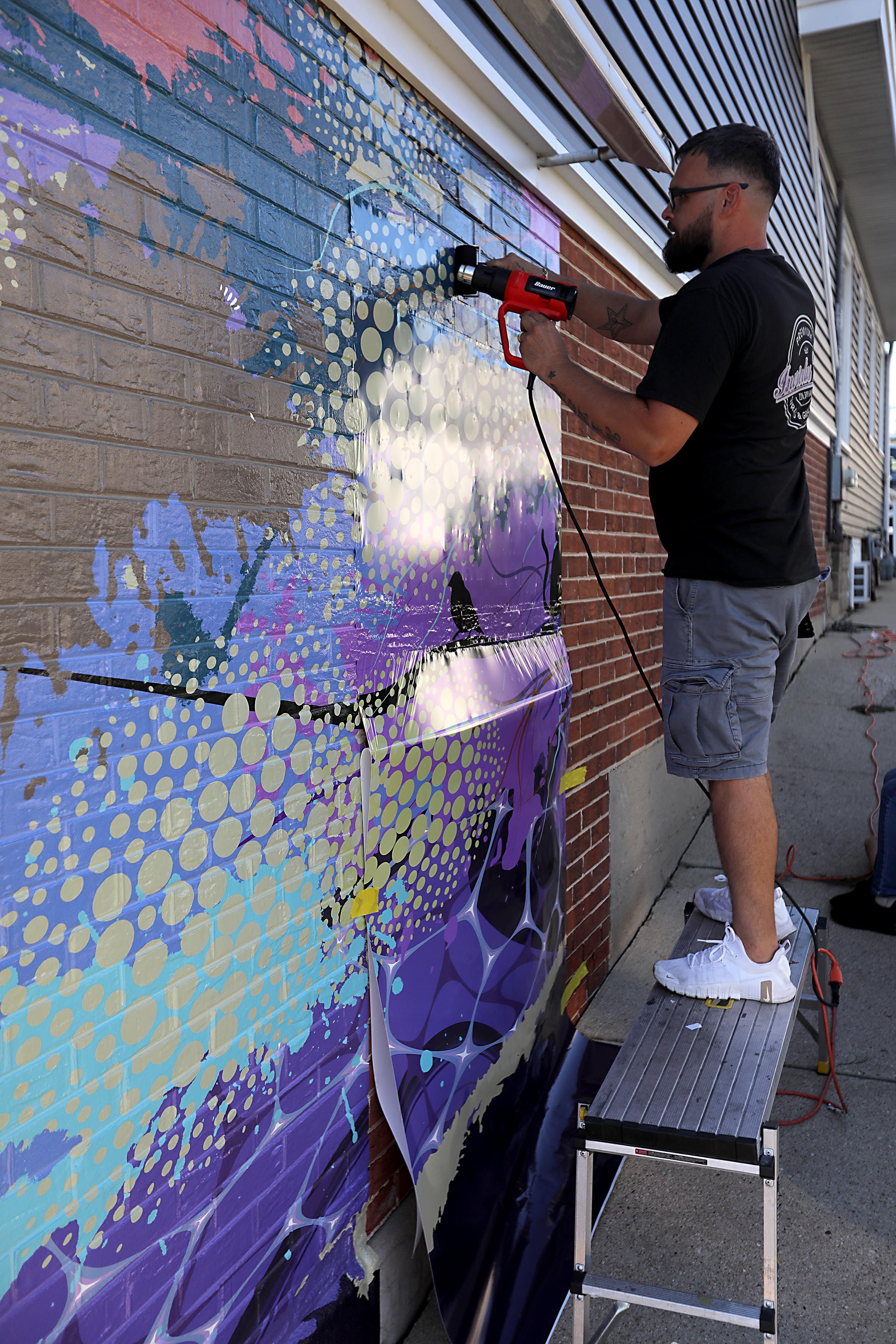 Mike Suchowski, of Invictus Vinyl, instals a new mural on Monday, Sept 15, 2025, on the side of a building at 3430 West Elm Street in McHenry. 