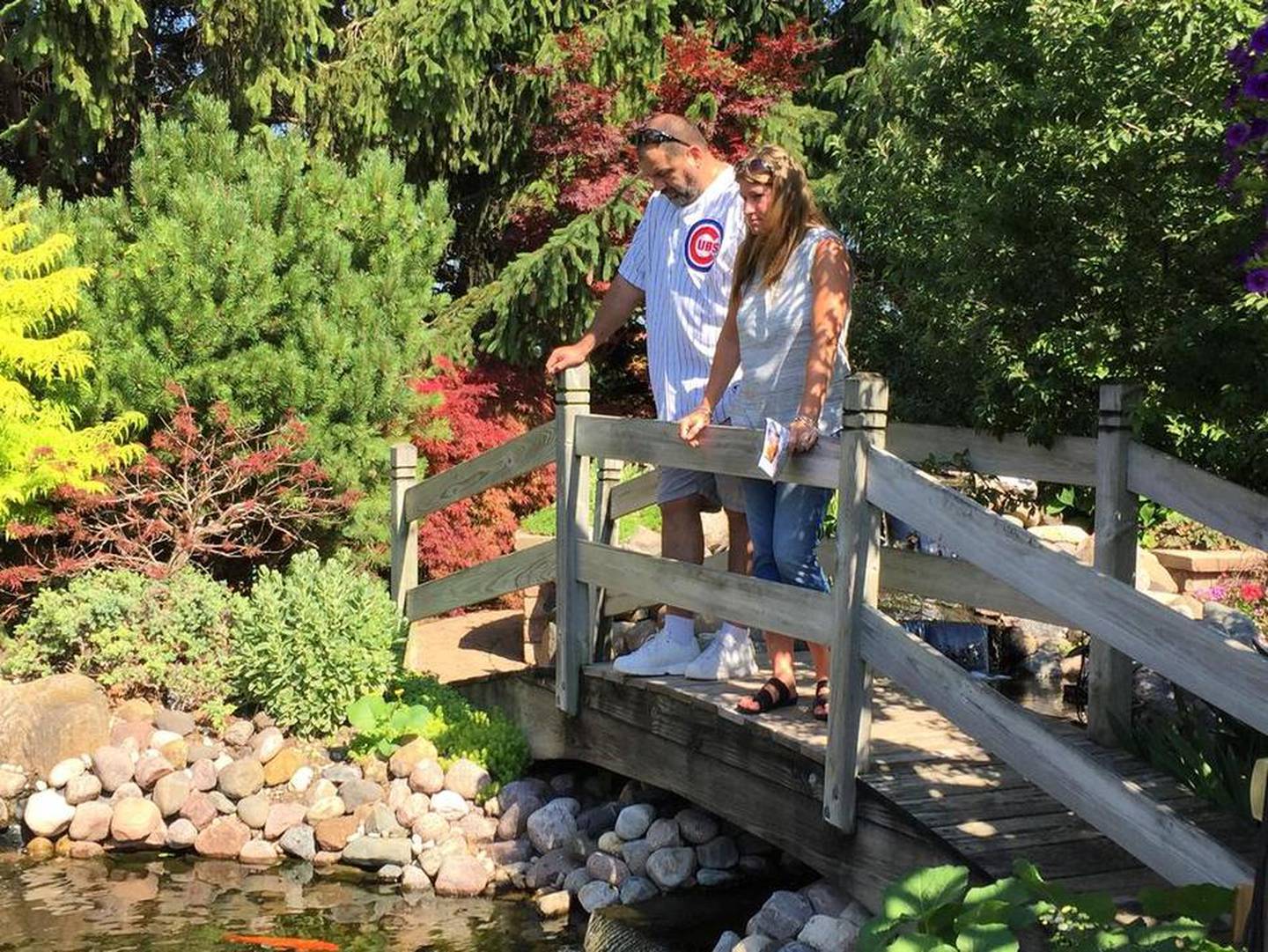 Lisa Garcia, right, and her husband Vince Garcia of Joliet view the pond and tree house at the Betsy and John Sullivan garden along the Timmy's Hugs and Hearts Garden Walk Saturday.