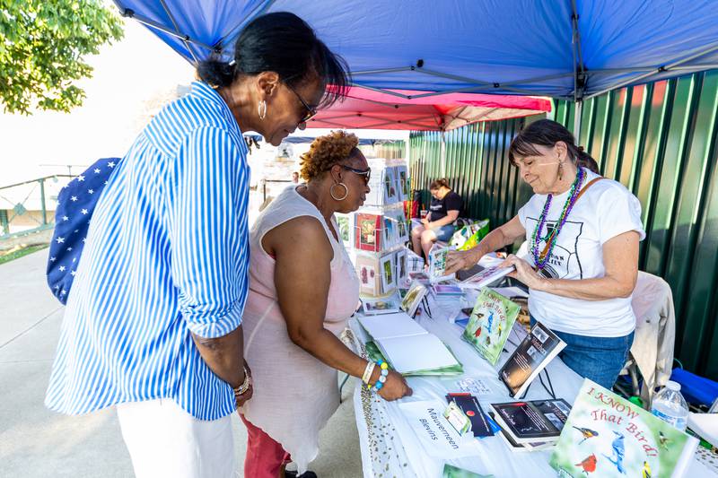 Joliet residents Gina Carter and Zandra McIntosh chat with author/photographer Mauverneen Blevins in the Artists Row area of New Orleans North Festival on Aug. 16, 2024.