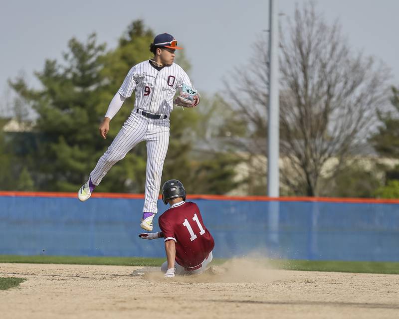 Plainfield North's Tanner Grimes (11) slides into second as the ball is thrown over Oswego's Gabe Herrera (9) head during baseball game between Plainfield North at Oswego, Thursday, April 24, 2025 in Oswego.