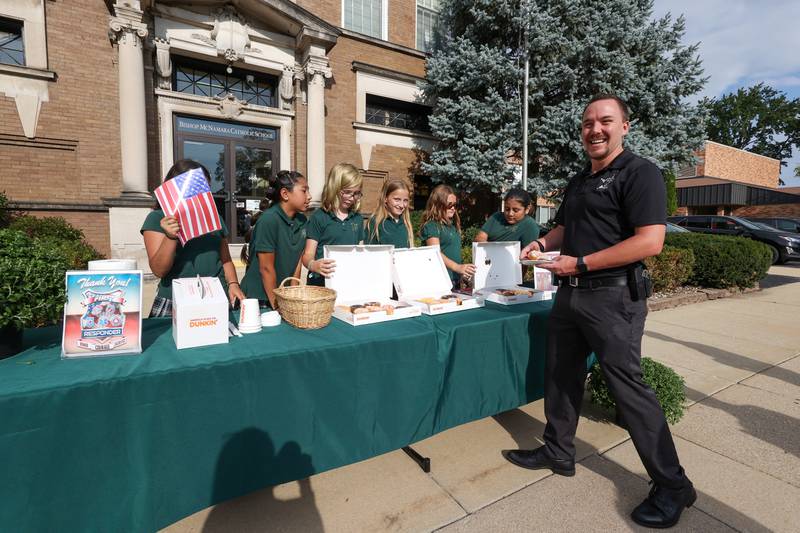 Bradley Police Detective Riley Pietraszewski smiles as he accepts a donut from Bishop McNamara Catholic School fifth graders as they host the 10th Gratitude Drive-Thru for first responders and military members on Thursday, Sept. 11, 2025.