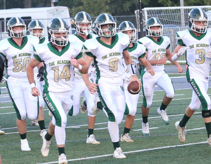 Members of the St. Bede football team run onto the field to play Tuscola on Friday, Aug. 25, 2023 at Tucci Stadium  in Bloomington.