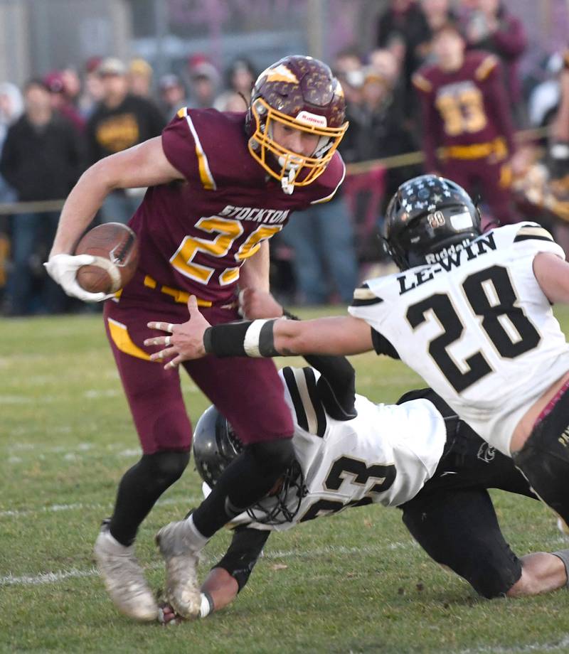 Stockton's Morgan Haas runs with the ball as Lena-Winslow's Tyree Davis (33) and Merrik Mahon (38) defend in 1A semifinal action on Saturday, Nov. 22, 2025 in Stockton.