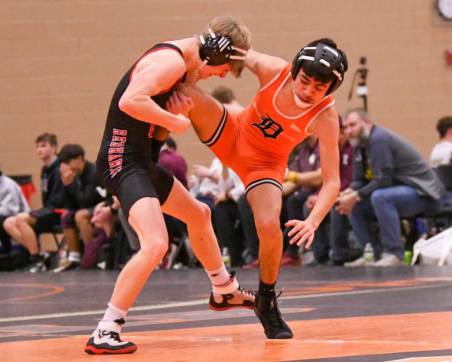 DeKalb's Daniel Sandoval keeps his balance as Naperville Central’s Jack Moore keeps a hold of his leg Saturday Dec. 28, 2024, in the 120-pound weight class of the Don Flavin Invite held at DeKalb High School.