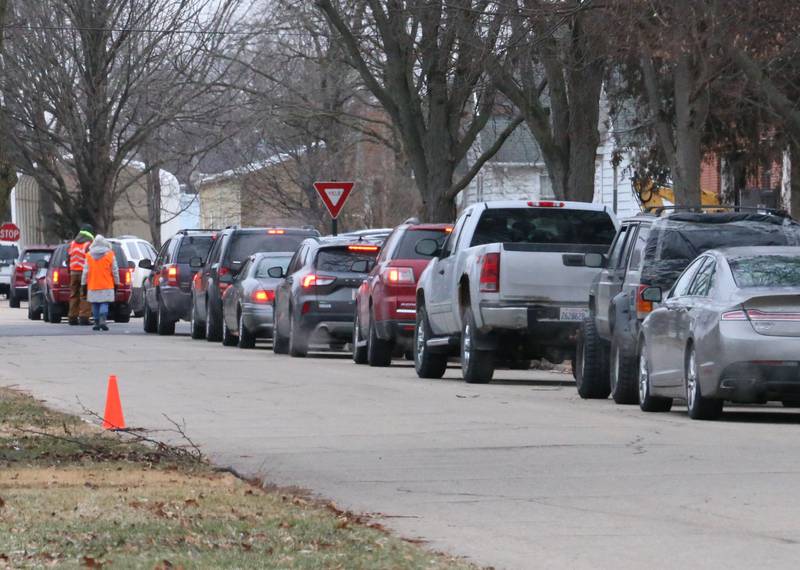 A long line of vehicles wait for food distribution at the Hall Township Food Pantry on Wednesday, Dec. 21, 2022 in Spring Valley.