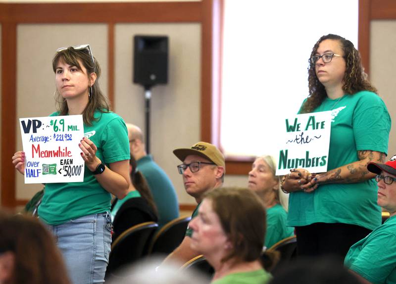 Northern Illinois University employees stand up and hold signs Thursday, June 12, 2025, during the NIU Board of Trustees meeting in Altgeld Hall at NIU in DeKalb. NIU clerical, professional and administrative workers represented by the American Federation of State, County and Municipal Employees Local 1890 are asking for higher wages when their contract expires at the end of the month.