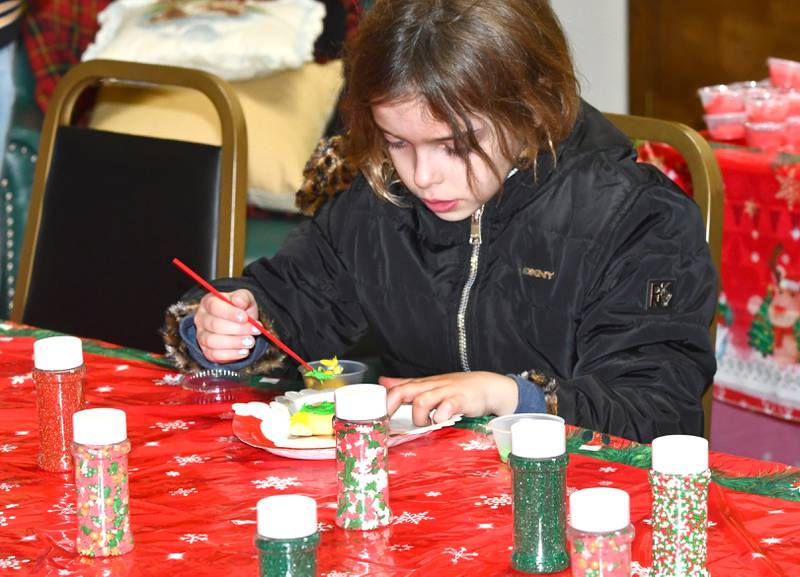 Bea Watt-May, 7, decorates a cookie with the help of Polo High School students at the Polo Senior Center during the Polo Christmas Festival on Saturday, Dec. 6, 2025.