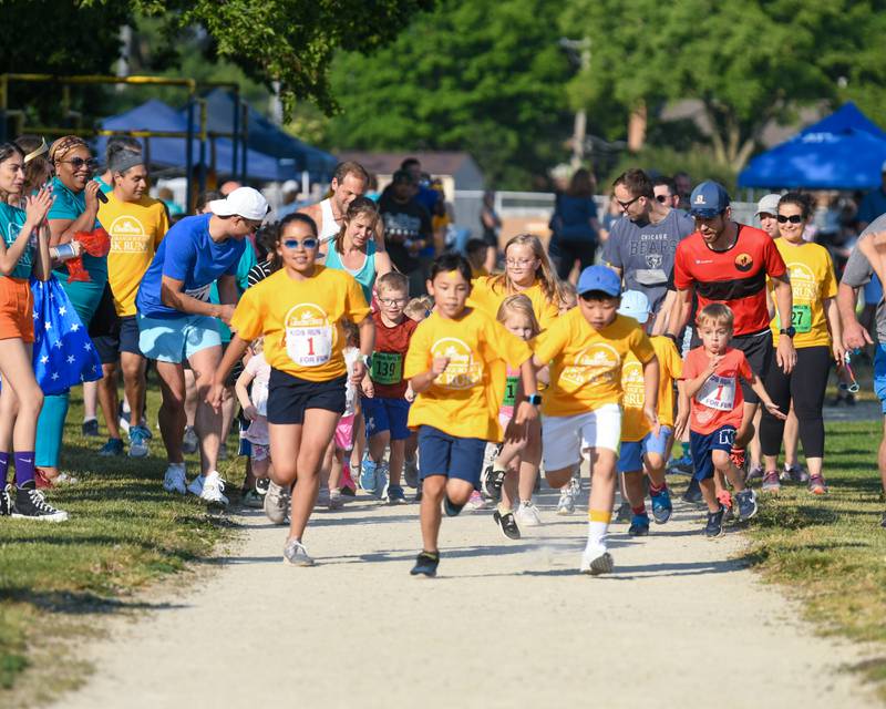 Young runners and walkers take a lap on the track of the Lyons Township practice field during the Leadership event held in La Grange on Friday June 9, 2023.