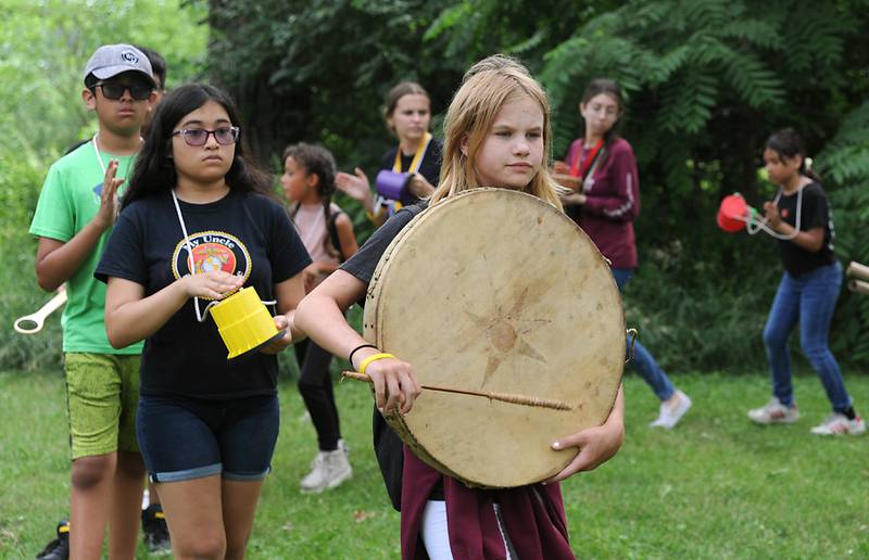 Carrington Davis,, 11, plays a drum as she marches  in a drum circle with other children from Youth and Family Center of McHenry County summer camp program during a field trip Wednesday, July 6, 2022, to the Harrison Benwell Conservation Area, 7055 McCullom Lake Road in Wonder Lake. The Youth and Family Center of McHenry County is hiring a social worker to assist with the mental health needs of those they help. The nonprofit is one of three receiving funds through United Way of Greater McHenry County as part of an Advance McHenry County grant.