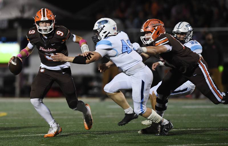 Hersey quarterback Jake Nawrot, left, tries to avoid a sack by Prospect's Colin Fouch as the Huskies’ Sebastian Singleton (17) tries to help on the play during Friday’s game in Arlington Heights.