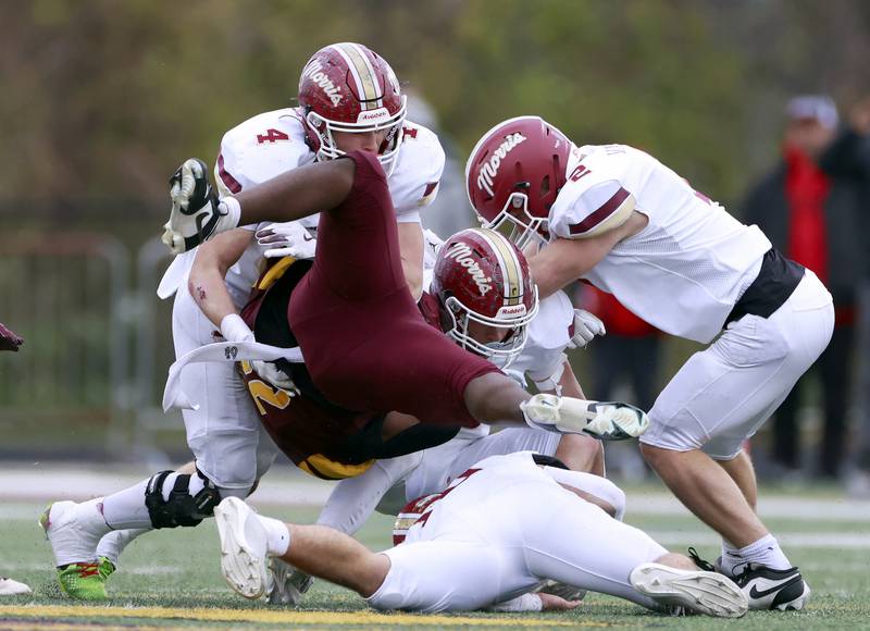 Montini's Isaac Alexander (28) is brought down by a host of Morris players including Mick Smith (4) and Bryce Varner (2) during the IHSA Class 4A semifinals football playoff game Saturday, Nov. 22, 2025 in Lombard.