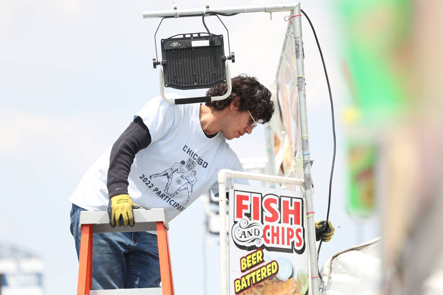 Sebastian Gonzalez works on a light for one of the food tents during the Taste of Joliet setup on Thursday, June 22, 2023.