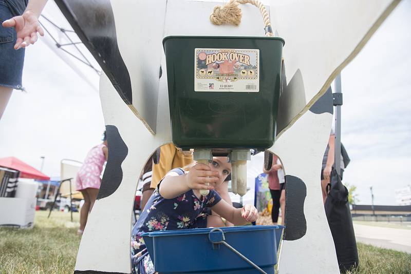 Vallarie Pennington, 4, of Dixon tries her hand at milking an fake cow Friday, June 24, 2022 at Rock Falls’ Summer Splash. The cow was set up by the Whiteside County Farm Bureau.
