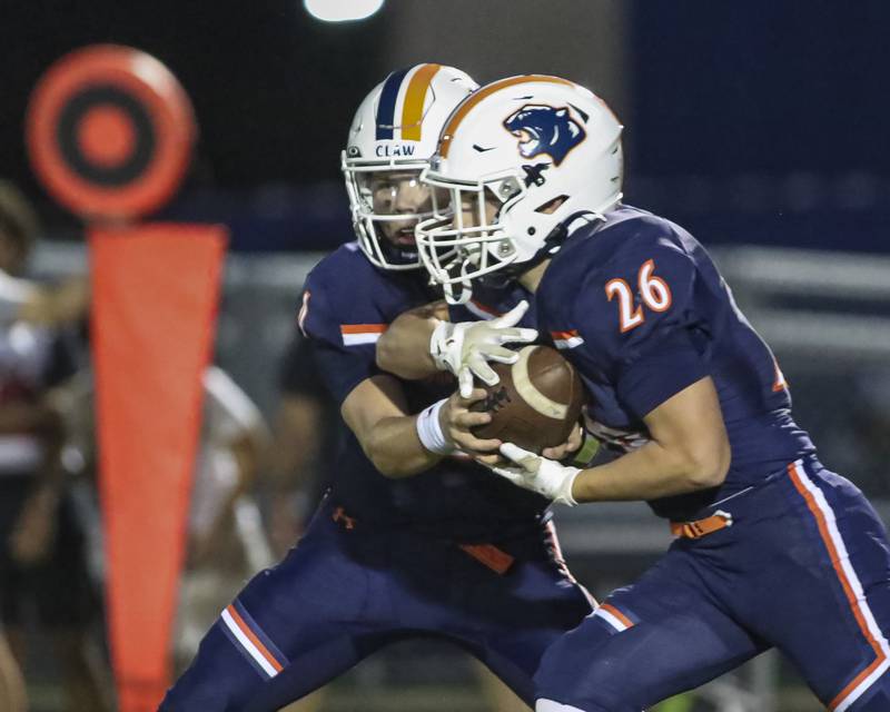 Oswego's Dekker Zelensek (26) takes the handoff from Drew Kleinhans (4) during football game between Yorkville at Oswego Friday, Sept 26, 2025 in Oswego.